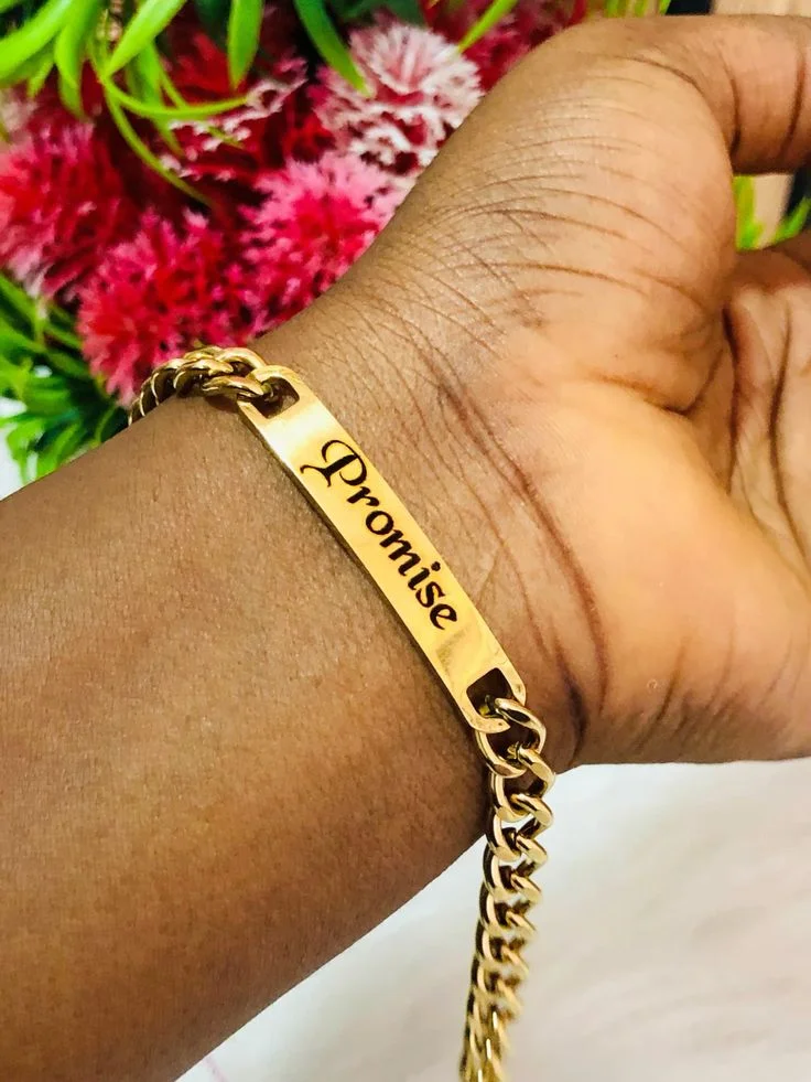 Gold chain bracelet with an engraved name plate worn on a wrist