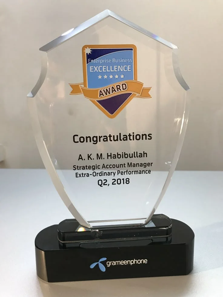 Clear shield-shaped presentation plaque with an engraved inscription on a black base