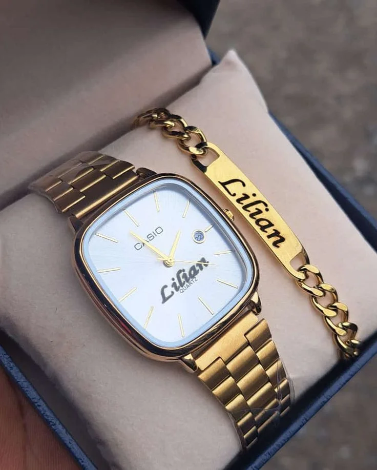 Gold watch and engraved bracelet arranged on a pale cushion