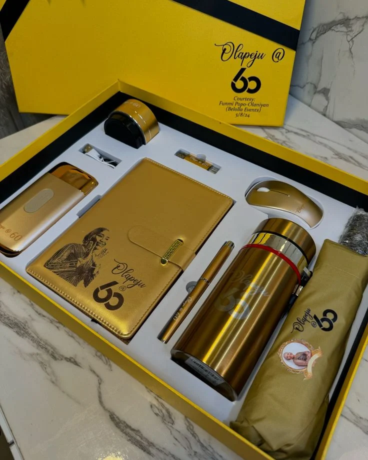 Gold flask, notebook and accessories arranged in a fitted yellow gift box