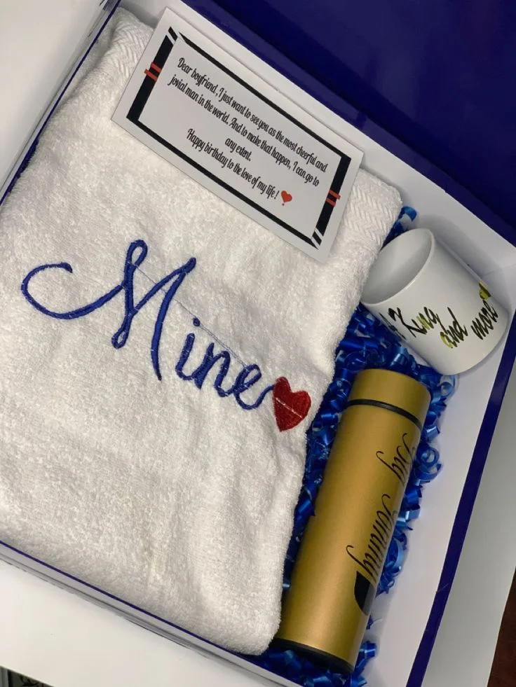 White embroidered towel, mug and flask arranged in a gift box