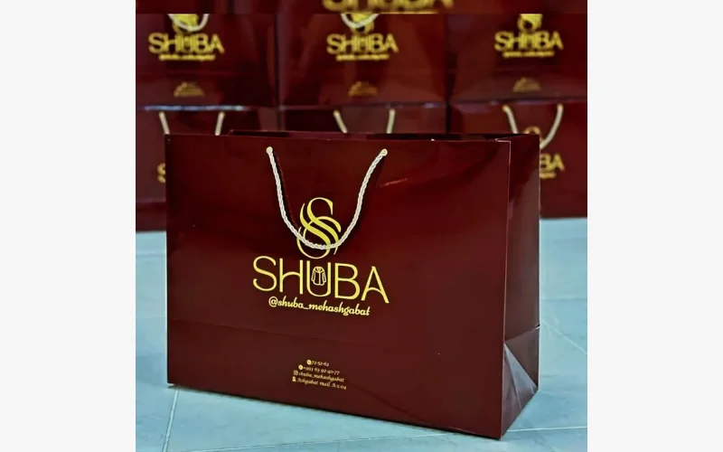 Burgundy shopping bags with gold SHUBA lettering and rope handles